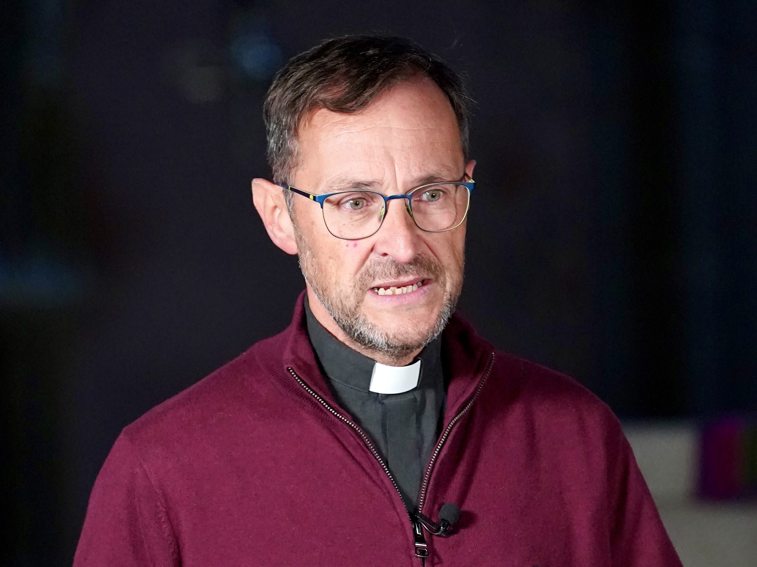 Pfarrer Jörg Meyrer mit rotem Pullover vor schwarzem Hintergrund